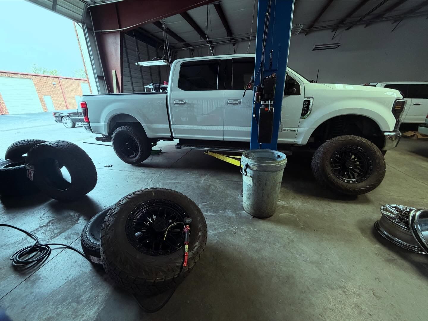 Lifted Ford Super Duty on the lift with off-road wheels staged at Unlimited Tire & Service in Buford, GA